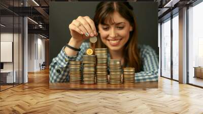 Smiling young woman stacking money and coins happy with her savings Wall mural