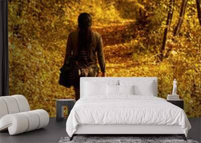 Back view of a female walking in a golden park on an autumn day Wall mural