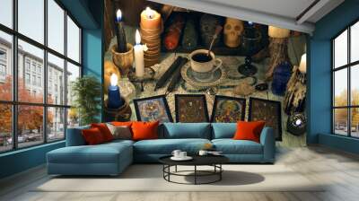 Fortune telling ritual with tarot cards, burning candles, cup of tea and crystals on wooden table. Wall mural