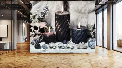 Grunge still life with crystal stones, burning candles and skull with flowers on witch altar table. Wall mural