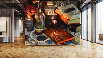 Still life with grimoire book of spells, burning candles, runes and ritual objects on witch table. Wall mural