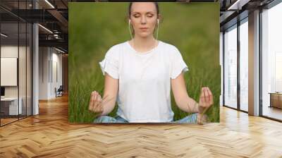 Beautiful young woman meditate on meadou na early summer evening Wall mural