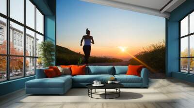 woman running on a mountain road at summer sunset Wall mural