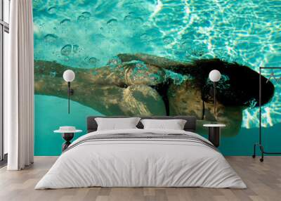 Woman swimming underwater in a blue pool. Wall mural