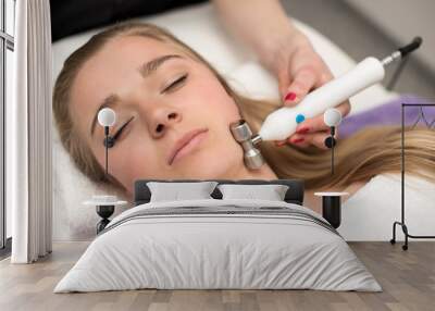 Young woman lying on massage table receiving face massage. Beaut Wall mural