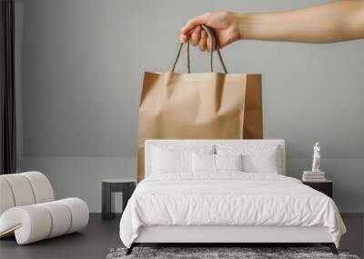 A hand holding a brown cardboard take-out bag with handles. Wall mural