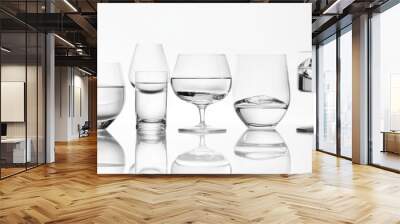 Multiple glasses with varying water levels, white background, abstract study of liquid balance and clarity Wall mural