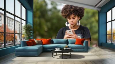 Outdoor portrait of a Young black African American young woman texting  on mobile phone Wall mural