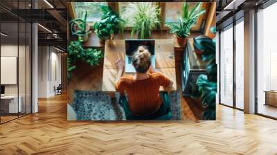 A photograph capturing a serene moment of a woman working on her laptop at home Wall mural