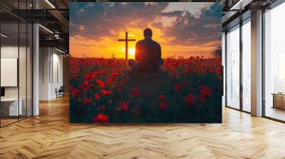 Man kneeling near the wooden Christian cross on a nature meadow grass field at sunset. Wall mural