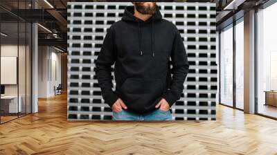 City portrait of handsome hipster guy with beard wearing black blank hoodie or sweatshirt and hat with space for your logo or design. Mockup for print Wall mural