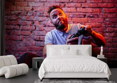 Emotional guy playing video game at home. Concept of gaming and technology. Relax Wall mural