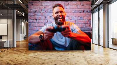 Emotional guy playing video game at home. Concept of gaming and technology. Relax Wall mural