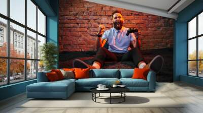 Emotional guy playing video game at home. Concept of gaming and technology. Relax Wall mural