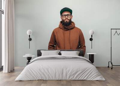 Handsome hipster guy with beard wearing brown blank hoodie or hoody and black cap with space for your logo or design on white background. Mockup for print Wall mural