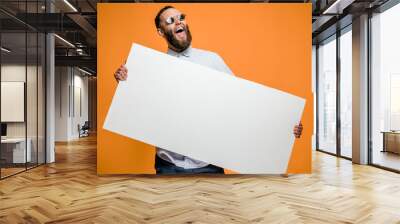 Hipster man holding a poster with blank space for your text. Wall mural