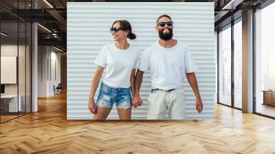 Young smiling couple in blank white t-shirts on street. Mockup for design. Wall mural