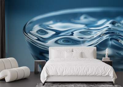 A wavy water surface in a glass fishbowl on a monochromatic blue background. The close-up exploration captures the intricate details of water ripples. Wall mural