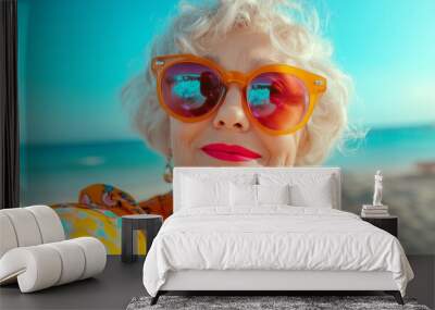 Selfie photo of an elderly female blogger in bright sunglasses and bright clothes, on the beach background. Wall mural