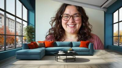 A  woman with curly brown hair and glasses, smiling at the camera Wall mural