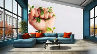 Woman hand, nature and fist with leaves for eco warrior, fight and revolution for sustainability protest. White background, studio and person with leaf and green plant in hands for environment rally Wall mural