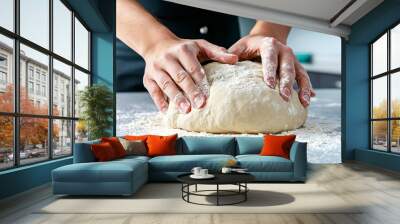 A person kneading dough on a floured countertop, with hands pressing and shaping the dough for homemade bread Wall mural