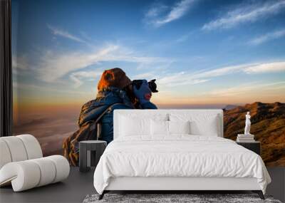 Beautiful women professional photographer takes images with DSLR camera., on the mountain with morning sunlight and fog. Wall mural