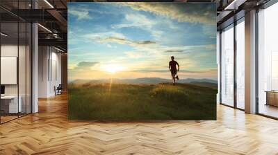 Athlete trailrunning in the mountains during a nice sunset. With shallow D.O.F. and motion blur. Wall mural