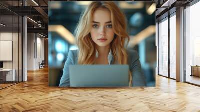 Beautiful young woman in a gray suit working on a laptop in the office, professional business portrait. Wall mural