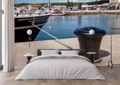 Fažana, Croatia, September 17, 2024. Ship anchored at a bollard in the lively fishing village of Fažana in Istria, Croatia. Harbor basin and restaurants with many visitors Wall mural