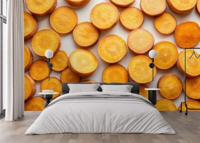 Freshly cut sweet potato slices arranged in a random pattern on a clean white background, showcasing their warm orange color and smooth texture. Wall mural