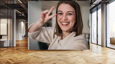 One young woman caucasian looking at the camera, smiling and making selfportrait or a video call Wall mural