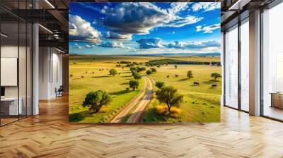 Serene landscape of vast, rolling llanuras under a bright blue sky with scattered trees, grazing cattle, and a winding dirt road disappearing into the horizon. Wall mural