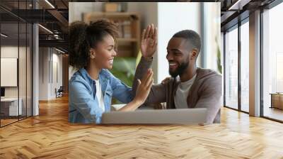 Couple on sofa using laptop and clapping Wall mural