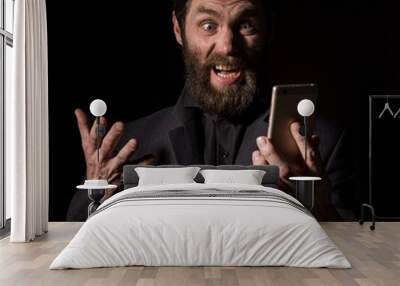 Old believer senior priest with a smartphone, bearded old man is calling on a dark background Wall mural