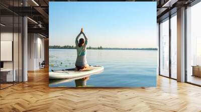 Female practicing yoga on a SUP board Wall mural