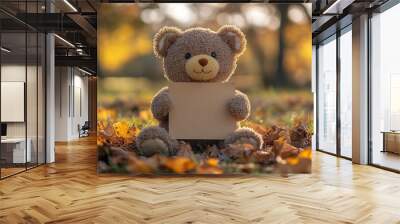 In the park, a cute teddy bear doll holds a blank brown paper board while sitting. Wall mural