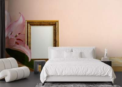 Empty picture frame with lily flower on wooden table. pink background Wall mural