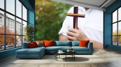 Closeup wooden cross that held by Asian man in white shirt. Concept : Christian worship.  Faith, forgiveness,belief, love and hope. Religious symbol of Christianity.       Wall mural