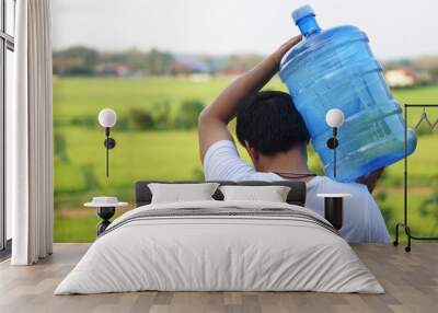 Man carrying a bottle of drinking water on his shoulder to service the villagers in rural of Thailand that lack of drinking water in summer. Concept healthy strong man. Service delivery man. Wall mural