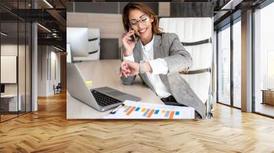 A business woman sits in her office and talks over a smart phone and arranges a new meeting with clients with a smile Wall mural