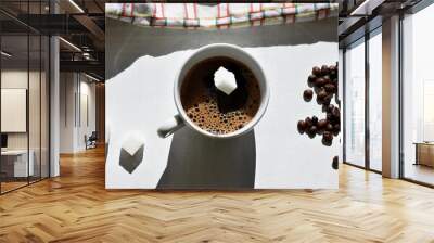 Sugar cube falling into a cup of coffee/A sugar cube dropped into a cup with black coffee. Falling sugar into a warm drink Coffee background concept Wall mural