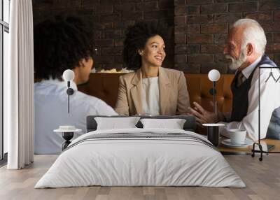 Three businesspeople talking in a stylish company lobby , discussing a business deal. Wall mural