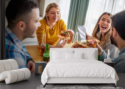 Group of cheerful friends eating delicious pizza at home Wall mural