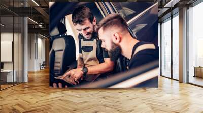 Mechanics using laptop while examining car engine Wall mural