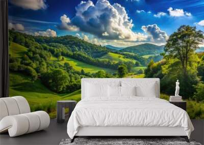 A winding asphalt road stretches into the distance, flanked by lush green trees and rolling hills, under a bright blue sky with puffy white clouds. Wall mural