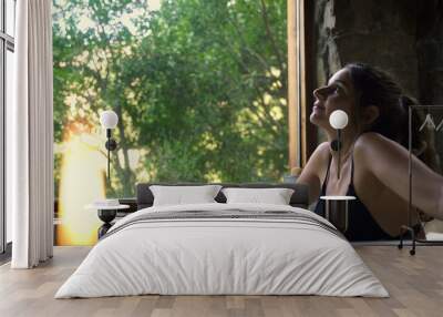 Young attractive female having a fancy bath in a hot tub spa with big green nature window Wall mural