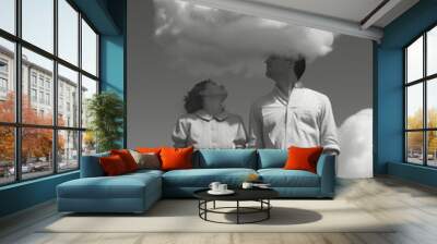 Young couple standing under white cloud together holding each other for hands. Love, cute, romantic scene. Wall mural