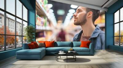 Young man shopping in a grocery store. Wall mural