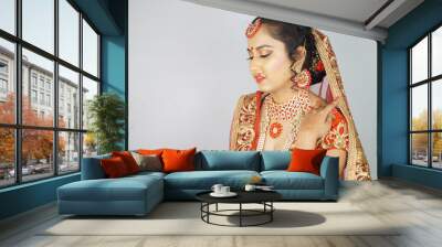 Beautiful Indian woman in a traditional red sari dress posing against a white wall Wall mural